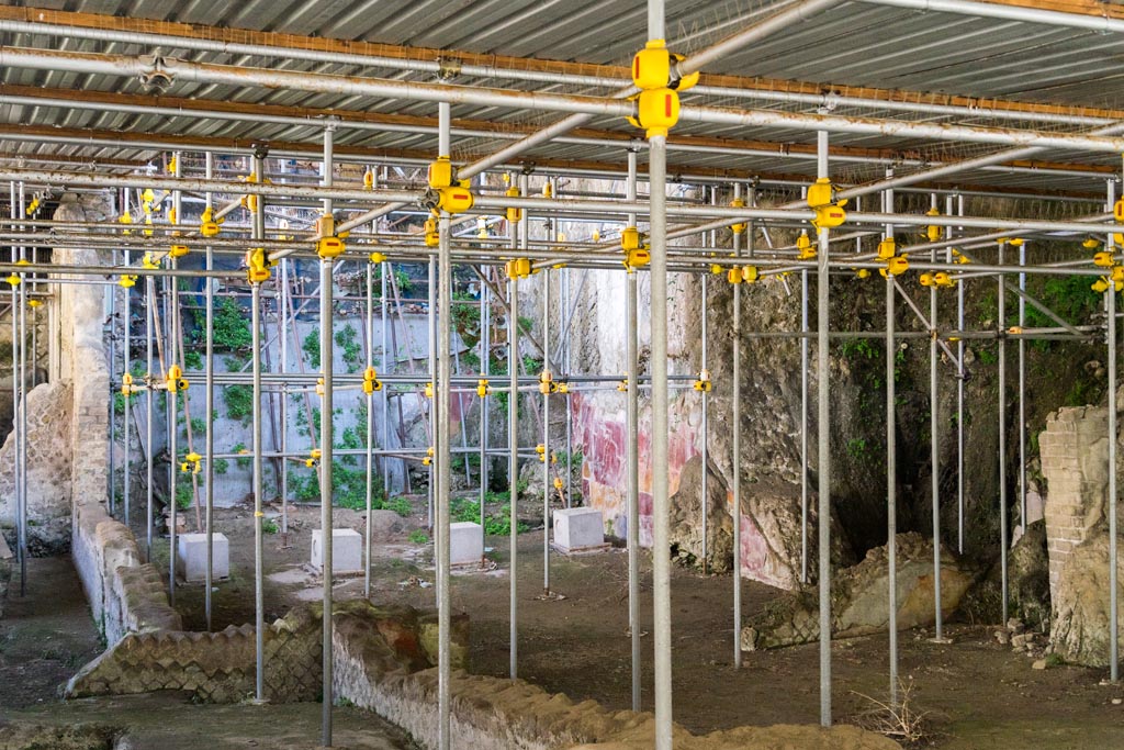 House of Dionysiac Reliefs, Herculaneum. October 2023.
Under the metal roof, at the side of the baths complex, is part of a large residential building. Photo courtesy of Johannes Eber.